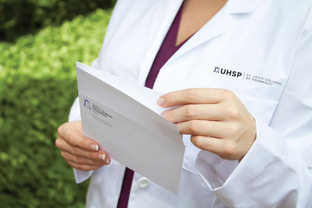 close up of female student in white coat opening a letter