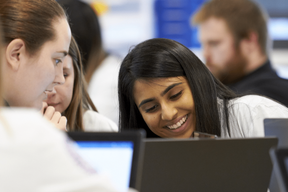 students smile while working on laptop