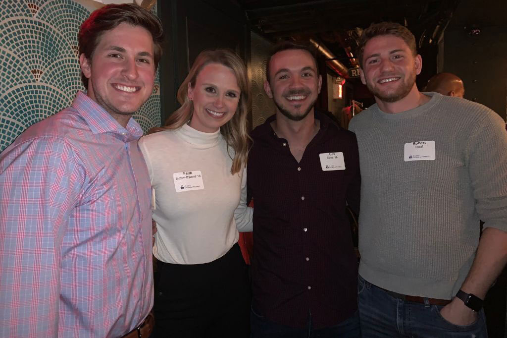 Four University alumni smile to the camera during an alumni reception